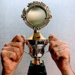 Close-up of hands holding a shiny trophy symbolizing achievement and victory.